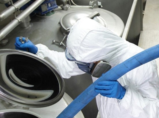 Industrie alimentaire - utilisation du tuyau Goodall DuraCrimp Food (le tuyau bleu est alimenté dans un réservoir par un employé en tenue de protection)